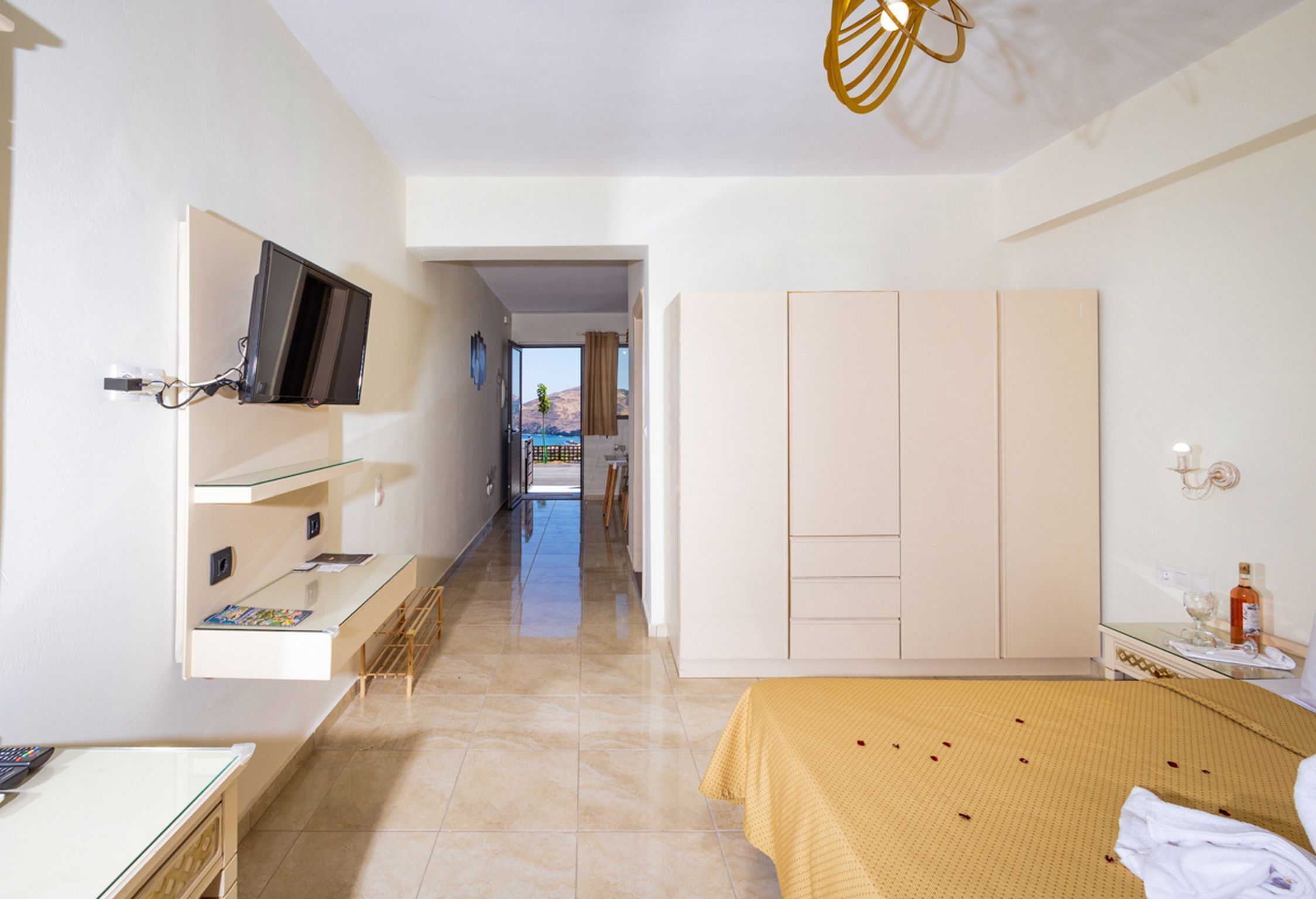 A hotel room with a bed, a desk, a TV mounted on the wall, and a wardrobe.