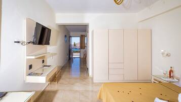 A hotel room with a bed, a desk, a TV mounted on the wall, and a wardrobe.