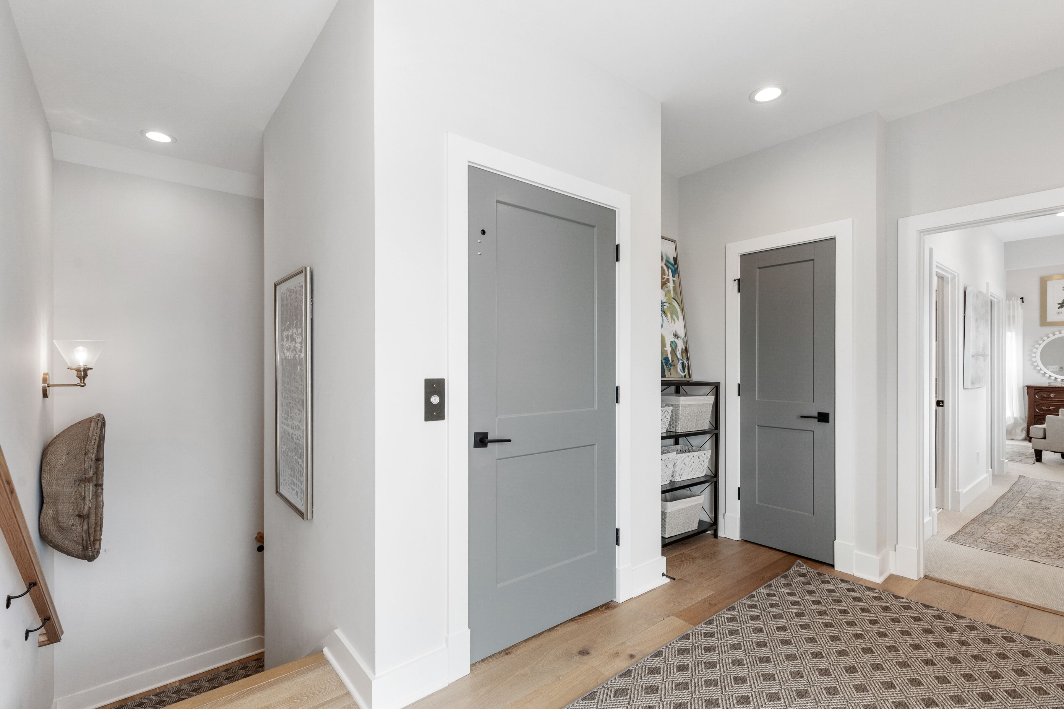 A hallway with white walls, grey doors, and a patterned rug.