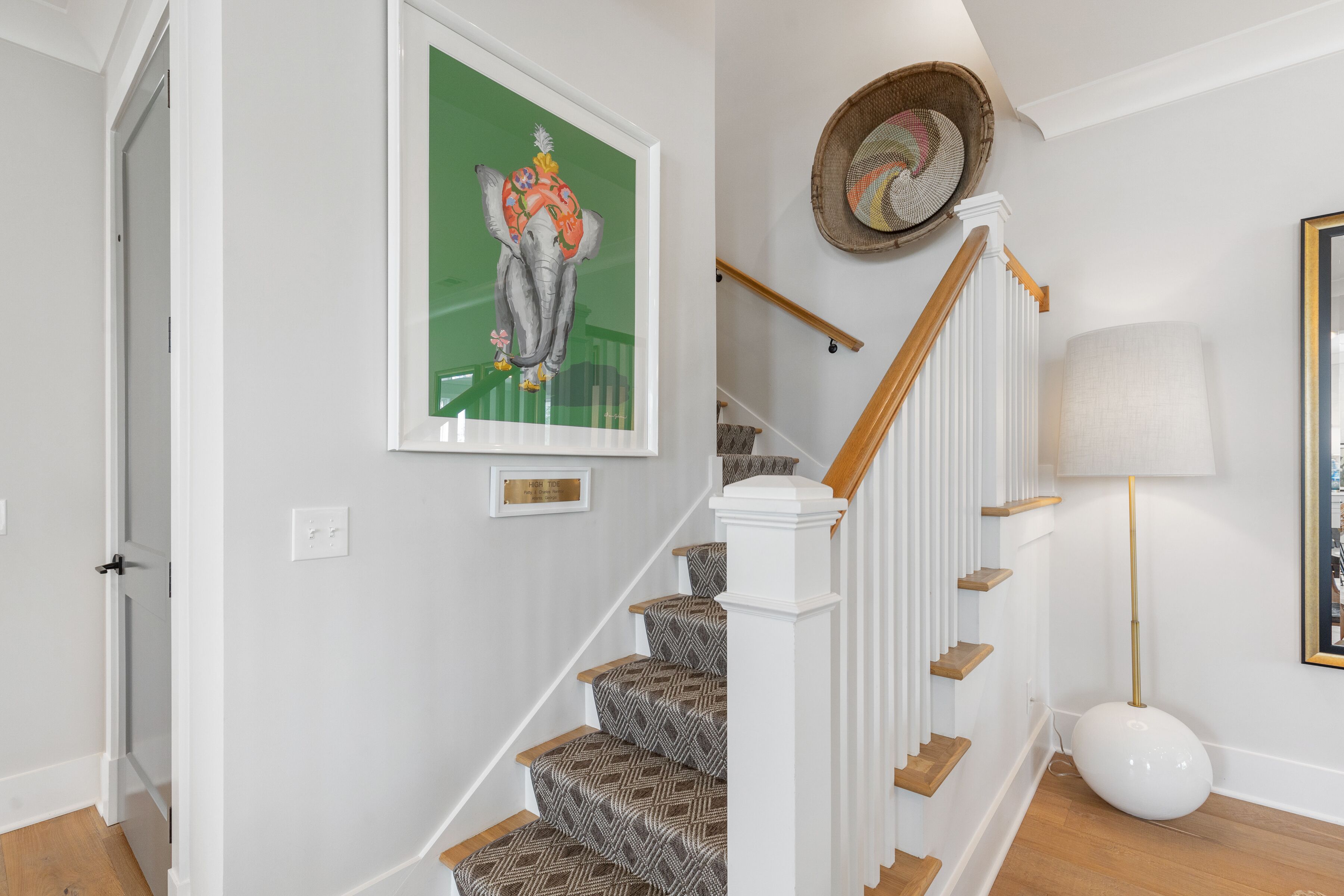 A staircase with patterned carpet, white railings, and a wall-mounted picture of an elephant.