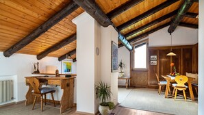 A rustic interior with exposed wooden beams, a wooden desk, a dining table with chairs, and a potted plant. - Apartment “Chalet Marianna” with Mountain View, Shared Terrace and Wi-Fi (Mölten)
