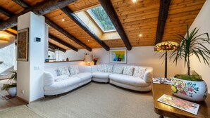 A cozy living room with a white sectional sofa, a wooden ceiling, and a skylight. - Apartment “Chalet Marianna” with Mountain View, Shared Terrace and Wi-Fi (Mölten)