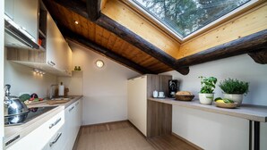 A modern kitchen with a skylight, wooden beams, white cabinetry, and a countertop with kitchenware and plants. - Apartment “Chalet Marianna” with Mountain View, Shared Terrace and Wi-Fi (Mölten)