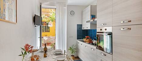 A compact kitchen with modern appliances, a dining area with a table set for four, and a view of the outside balcony.