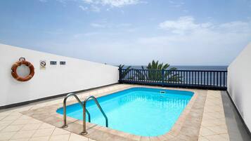 A rooftop swimming pool with a lifebuoy, a no diving sign, and a view of the ocean.