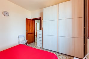 A bedroom with a bed, a wardrobe, a chair, a dresser, and a clock on the wall.