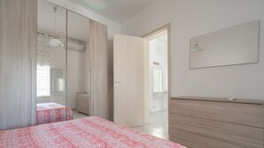 Une chambre à coucher comprenant un lit, une commode, un miroir et une porte donnant sur une autre pièce.