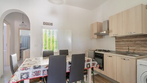 Une cuisine moderne avec un coin repas, des meubles en bois, un four encastré et un lave-linge.