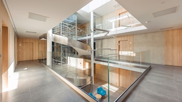 Un interior moderno con una escalera de cristal, una puerta de madera con la leyenda '13', y una silla azul.