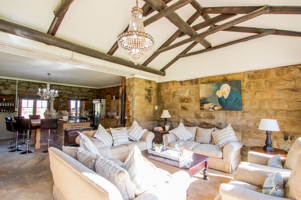 A spacious living area with a stone wall, a chandelier, and a painting.