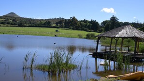 A tranquil lakeside scene with a wooden gazebo, a dock, and a distant mountain. - Flitwick Ranch - Bull Stables Room 9 (Greater Kokstad)