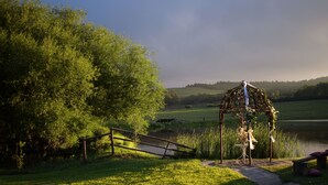 A gazebo with a rustic design, surrounded by lush greenery and a calm lake. - Flitwick Ranch - Bull Stables Room 9 (Greater Kokstad)