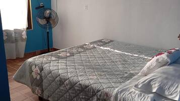 Relax in this cozy bedroom with a single bed, flat-screen TV, and standing fan.