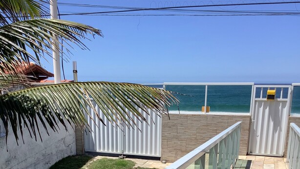A balcony with a metal railing, a small grassy area, and a view of the ocean. - Beach bed and Breakfast (Saquarema)