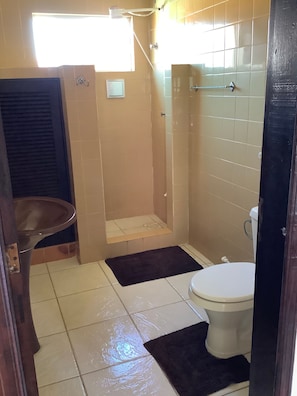 A small bathroom with a toilet, a sink, and a shower area.