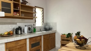 Una cocina con armarios de madera, una cafetera, un frutero y una ventana.
