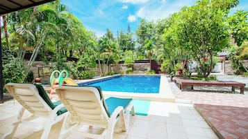 A swimming pool with lounge chairs and a covered patio area.