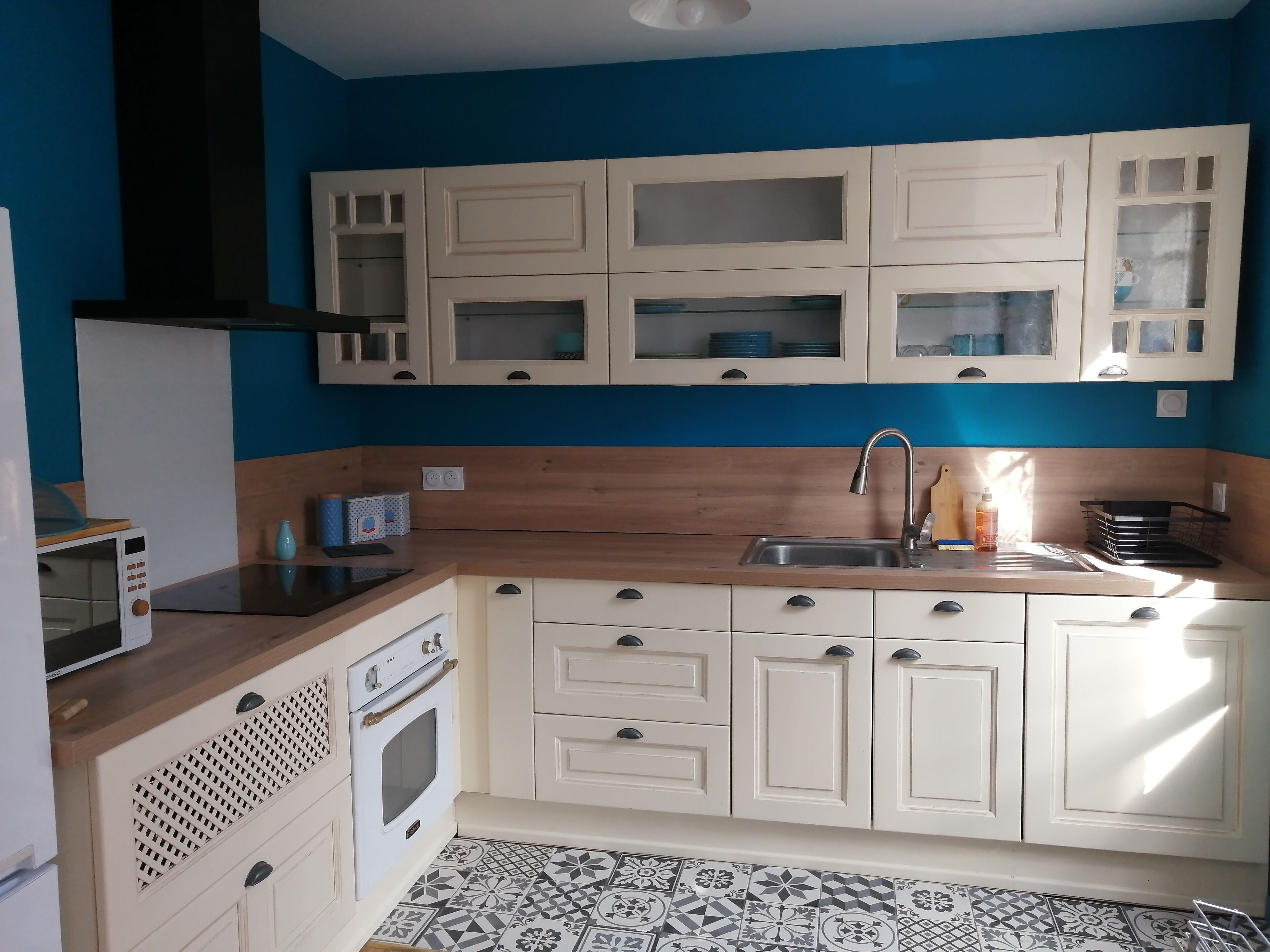 A kitchen with white cabinets, a wooden countertop, a sink, a microwave, and an oven.