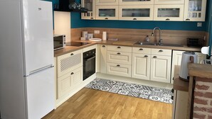 A compact kitchen with white cabinets, a built-in oven, a microwave, and a sink.