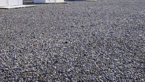 A pebbled beach with colorful buildings in the background.