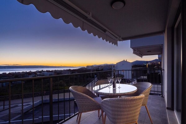 Enjoy the stunning coastal views from this balcony with a round table and wicker chairs.