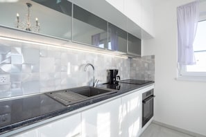Enjoy cooking in this kitchen with a stainless steel sink, oven, and coffee maker.