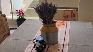 Een tafel met een zeester decoratie, een vaas met gedroogde bloemen en een lantaarn op een balkon met uitzicht op een kustgebied met palmbomen en zee.