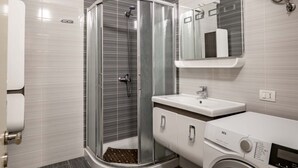 Een moderne badkamer met douche, toilet, wastafel en wasmachine.