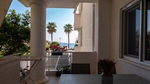 Een balkon met uitzicht op de zee, palmbomen en een betegelde vloer.