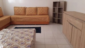Um quarto com sofá, cama, um pequeno armário e estante.
