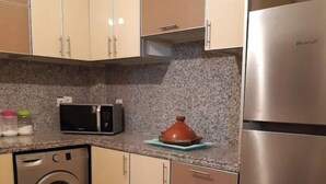 Uma cozinha compacta com máquina de lavar, micro-ondas e frigorífico.