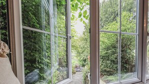 A room with a large window offering a view of a lush garden.