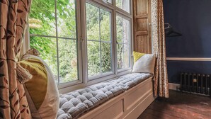 A cozy room with a built-in bench by a large window, offering a view of greenery outside.