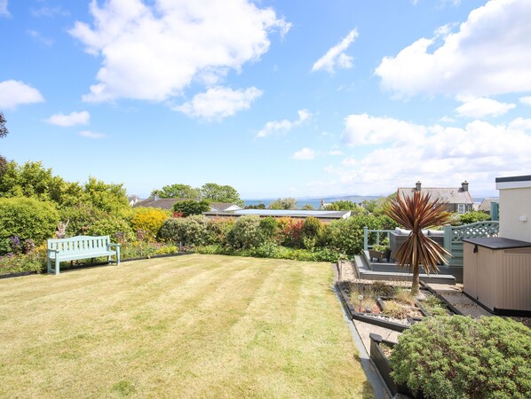 A well-maintained garden with a lawn, a bench, and various plants.