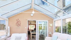 Uma sala de estar moderna com teto de vidro, área de jantar e vista para o exterior.