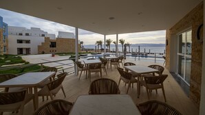 Une terrasse avec des sièges extérieurs, une piscine et une vue sur la mer.