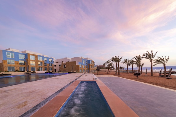 Un resort con varias piscinas, una zona de playa y palmeras.