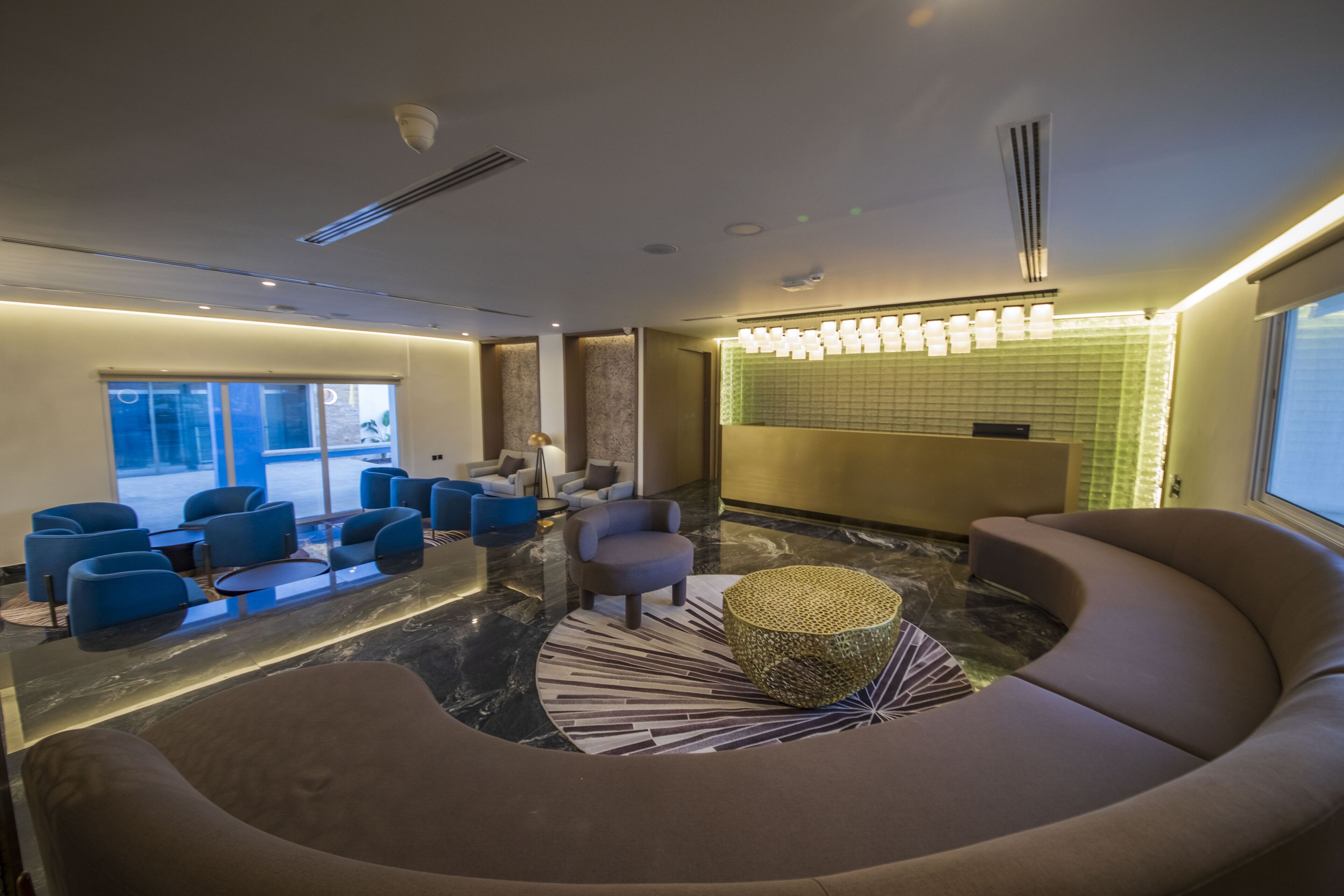 A modern lobby with seating areas, a reception desk, and a large window providing a view.