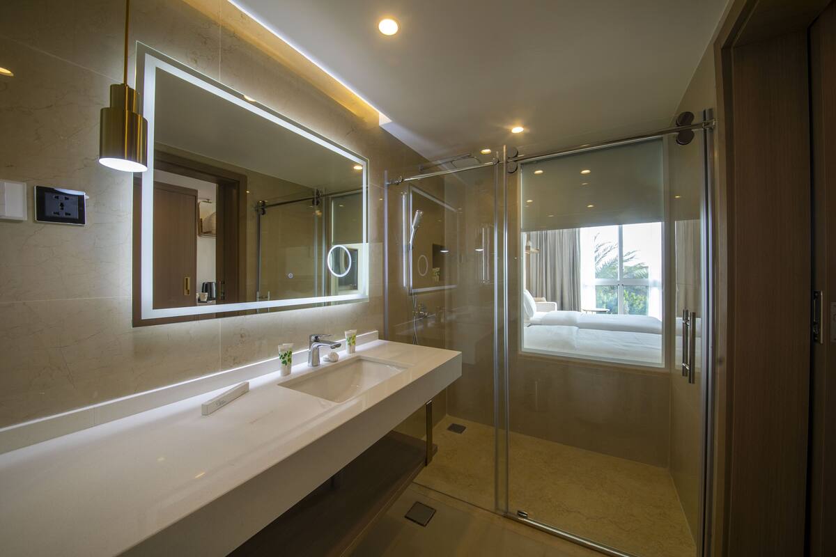 Une salle de bain moderne avec un grand miroir, deux lavabos et une douche à parois de verre.