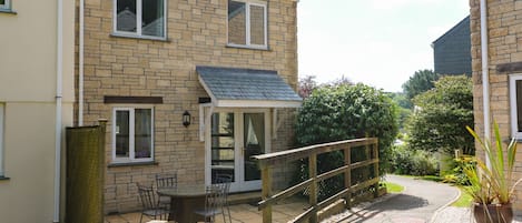 A two-story house with a patio area, a wooden fence, and a potted plant.