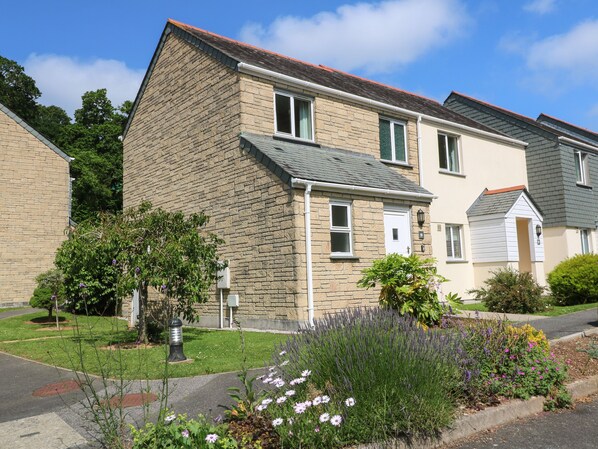 A two-story residential building with a stone facade, multiple windows, and a well-maintained garden with various plants and flowers. - Blackbird Cottage (Falmouth)