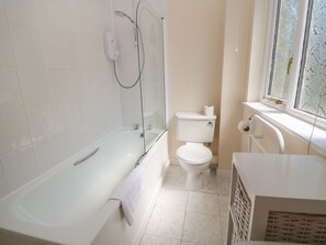 A bathroom with a bathtub, toilet, and a window. - Blackbird Cottage (Falmouth)
