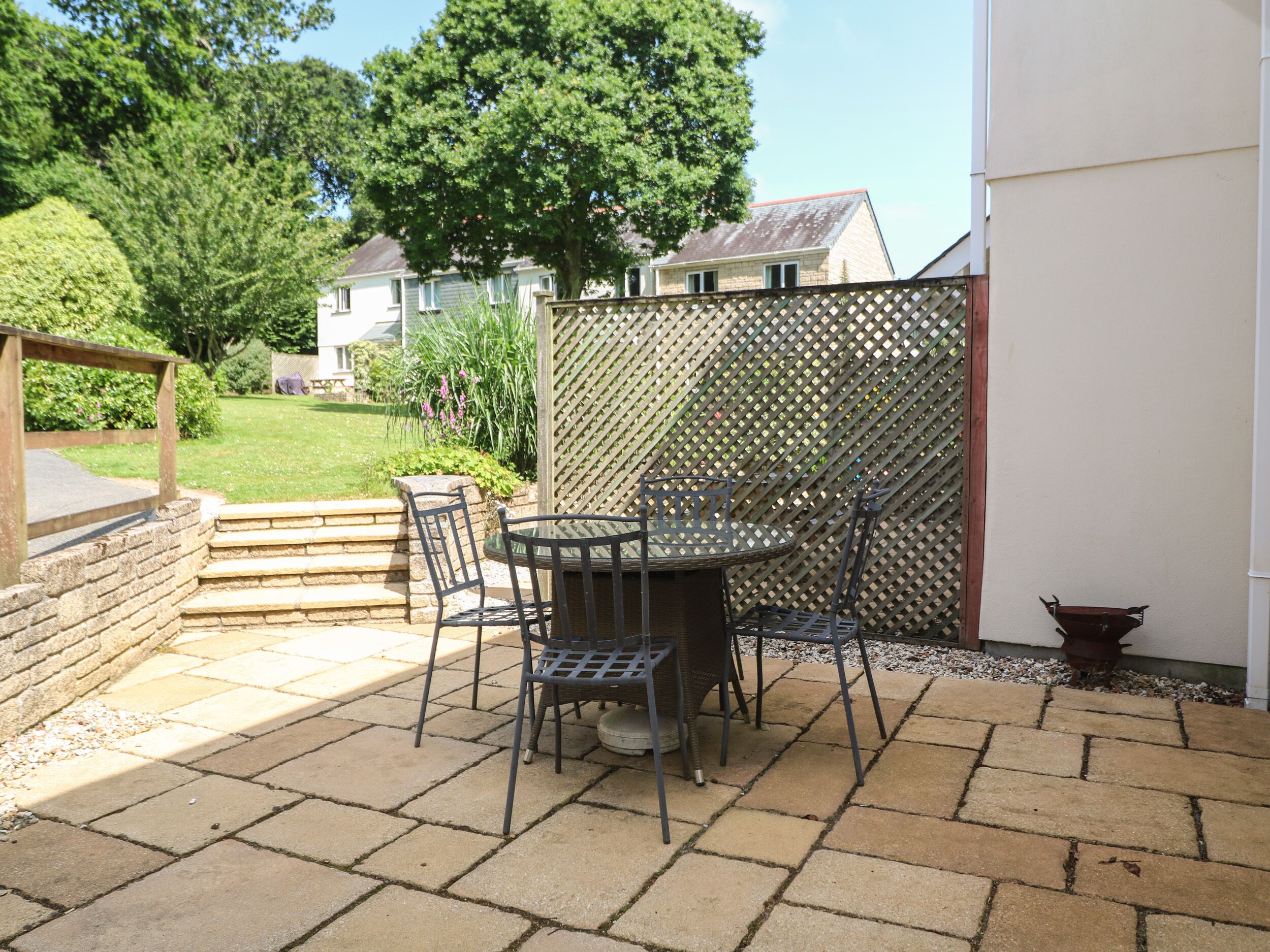 An outdoor patio with a round table and four chairs, surrounded by a lattice fence.