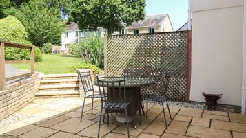 An outdoor patio with a round table and four chairs, surrounded by a lattice fence.