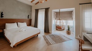 A spacious bedroom with a large bed, wooden beams, a hanging chair, and a view through a window. - Paye Alaçatı (Cesme)