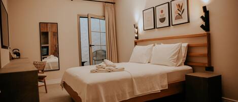 A neatly arranged bedroom with a bed, a chair, a desk, and a door leading to a balcony.