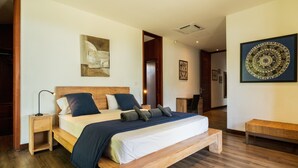 A bedroom with a wooden bed, a nightstand, a bench, and artwork on the walls. - Villa Paolita  (Vieux Grand Port)