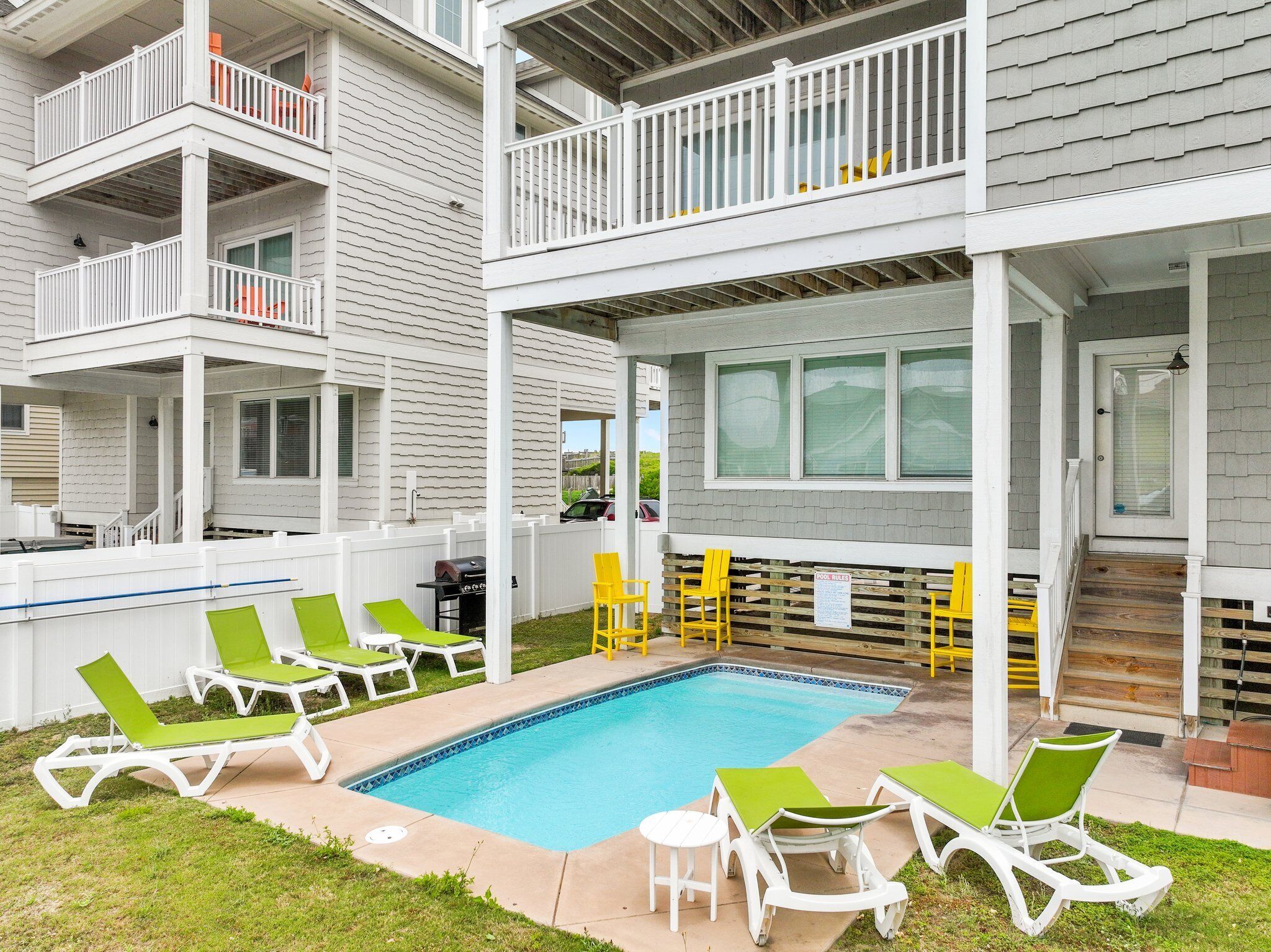 A two-story building with a pool, outdoor seating, and a covered patio area.