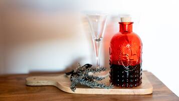 A wooden table with a red bottle, a clear glass, and a decorative branch.