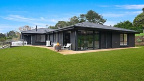 A modern two-story house with large glass doors and a patio area. - Hoddle Lane – rural views, fireplace and air conditioning (Robertson)